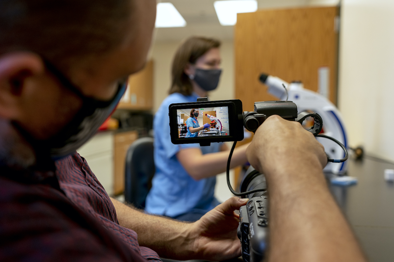 Scientist conducting research while being filmed with video camera